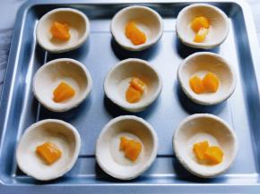 首先将黄桃罐头切小块，放入蛋挞皮中。