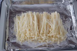 烤盘铺上锡纸，把金针菇均匀在放在锡纸上