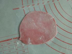 红色面团擀薄片，用模具压出花形来，分别粘到女娃娃的身体上