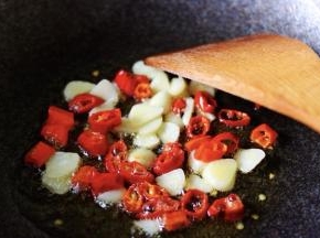 热锅倒入花生油烧热后放入大蒜片和红辣椒丁爆出香味后