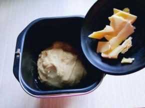 揉面15分钟后，加入提前室温软化的黄油。继续启动面包机揉面15分钟，这时面团已经有手套膜。
