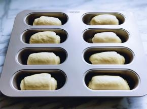 取一块面团，用擀面杖擀长舌状，再卷起来，放入模具中。