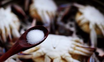 这个时候用勺子挖上适量的盐，均匀滴撒在梭子蟹身上；

