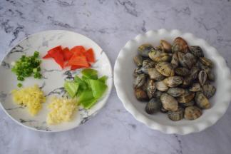 花蛤吐沙干净洗净沥干水分备用，青红椒去籽洗净切小块，蒜姜切末，葱切葱花