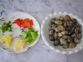 花蛤吐沙干净洗净沥干水分备用，青红椒去籽洗净切小块，蒜姜切末，葱切葱花