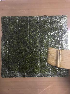 取一片海苔，在粗糙的面刷上酱料，刷满每个角落哦！