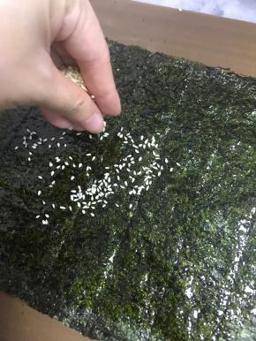 把芝麻均匀撒在刷满酱料的海苔片上。