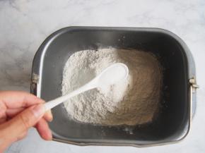 将面粉、奶粉放入面包机桶中，在一侧角落里放入盐。v