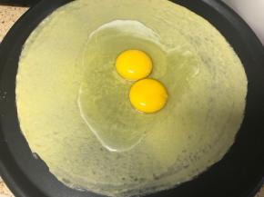 锅烧热，倒入少许的油抹匀锅底，如果是不粘效果特别好的锅可以不用抹。锅烧到用手摸时有点烫的程度时将锅调到最低火，向锅内舀入一汤勺的面糊或者根据自己锅的大小确定面糊量。立即转动煎饼果子工具，使面糊均匀铺满锅面，打入一只到两只鸡蛋。
