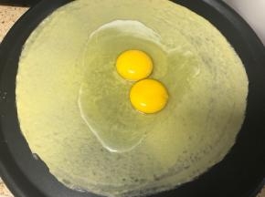 锅烧热，倒入少许的油抹匀锅底，如果是不粘效果特别好的锅可以不用抹。锅烧到用手摸时有点烫的程度时将锅调到最低火，向锅内舀入一汤勺的面糊或者根据自己锅的大小确定面糊量。立即转动煎饼果子工具，使面糊均匀铺满锅面，打入一只到两只鸡蛋。