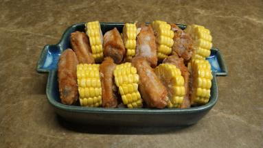 红萝卜、玉米切小片和段，红萝卜放烤盘底，一段玉米一块鸡翅隔着摆好