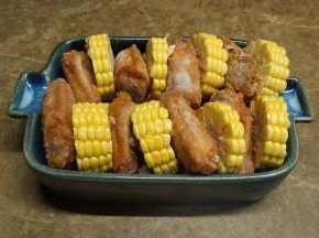 红萝卜、玉米切小片和段，红萝卜放烤盘底，一段玉米一块鸡翅隔着摆好