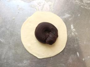 取一个面团擀成中间厚边缘薄的略厚的面片，加入10g的豆沙，这个豆沙的量可以随着口感增减