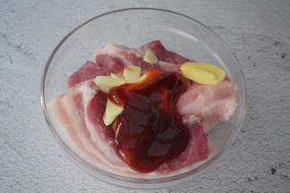 把五花肉放入容器中，加入姜蒜片、叉烧酱