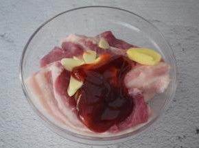 把五花肉放入容器中，加入姜蒜片、叉烧酱