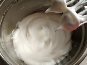 蛋清分次加入白糖和少许柠檬汁，用电动打蛋器打发至接近干性发泡状态。
