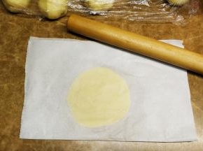 酥皮分成25g一分，放在油纸里，再盖上一层油纸，用手压平压圆