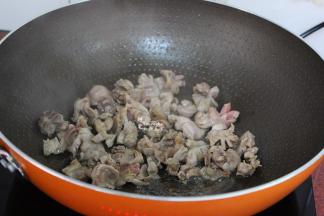 改为大火，倒入鸡胗、生姜爆炒，让鸡胗微微焦黄。