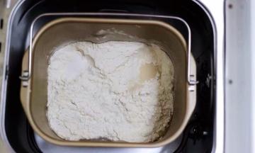 把奶粉、砂糖、全蛋液和牛奶倒入面包桶里，再加入高筋面粉后，盐和酵母不要放到一个地方，然后用面粉盖上；