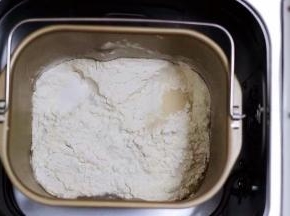 把奶粉、砂糖、全蛋液和牛奶倒入面包桶里，再加入高筋面粉后，盐和酵母不要放到一个地方，然后用面粉盖上；