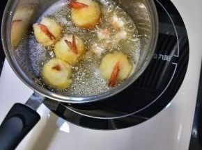 锅里放足够的花生油，五六成热时放入虾球，炸至金黄即可捞出沥油。