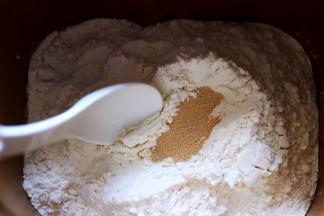 除黄油外的食材全部加入面包桶，盐和糖对角放，鸡蛋1个，奶粉，再加入高筋面粉，最后再面粉的顶端挖个洞，把酵母粉加入洞洞里，再用周边的面粉盖起来