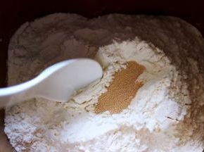 除黄油外的食材全部加入面包桶，盐和糖对角放，鸡蛋1个，奶粉，再加入高筋面粉，最后再面粉的顶端挖个洞，把酵母粉加入洞洞里，再用周边的面粉盖起来