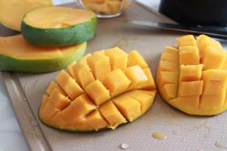 接着我们来制作椰奶芒果糊，大芒果沿着核切2半，横竖划几道，不要割破皮哦。