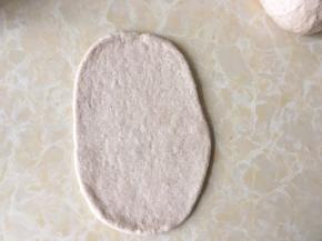 取一份松弛好的面团，用擀面杖擀成椭圆形