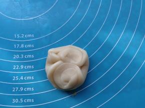 在饼皮的中间按压一下，然后把饼皮压扁，形成圆形状。