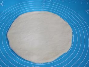 把面团取出按压排气，擀成跟披萨盘一样大小的圆形