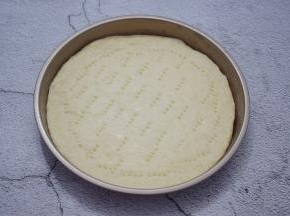 然后放入披萨盘，用叉子在饼皮叉些小洞
