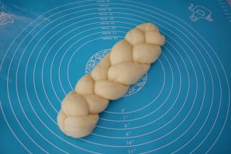 编出一个三股辫子，前后要捏归紧，然后放在底部，压住，这样发酵时不会松开