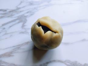 取一块月饼皮捏圆，包上馅料，以下往上推拿的手势包起来！