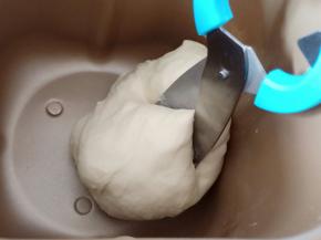 黄油揉匀之后，面团光滑了，我们用干净的剪刀在面团的上面剪开。当面团再次揉光滑的时候再剪开，反复重复这个动作。