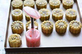 月饼模具转移到烤盘上，用力按压月饼模具，然后轻轻提起月饼模具，让月饼成型，放在烤盘上