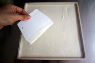 将蛋糕糊倒入烤盘，用刮板抹平表面。