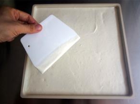 将蛋糕糊倒入烤盘，用刮板抹平表面。