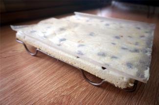 将蛋糕倒扣到方形冷却架上，撕开底部的油纸，盖回去。蛋糕表面的漂亮纹路正是冷却架的压痕。