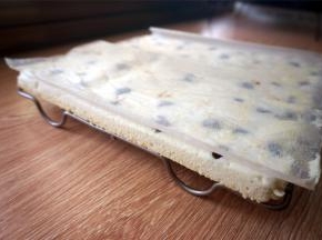 将蛋糕倒扣到方形冷却架上，撕开底部的油纸，盖回去。蛋糕表面的漂亮纹路正是冷却架的压痕。