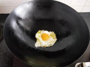 锅中加入适量的油，打入一个鸡蛋，煎至两面金黄放在一旁备用