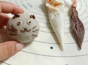 出炉放凉后，把黑、白巧克力隔水加热化开装进裱花袋里装饰上表情即可。