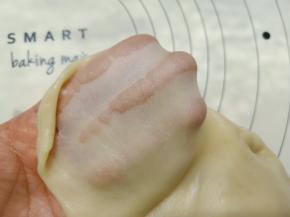 揉成团后再放面板上多揉一会。像做面包一样揉面，揉到能拉出膜，放入盆里盖保鲜膜醒30分钟，30分钟后看一下面团的状态，拉出薄而有韧性的膜。