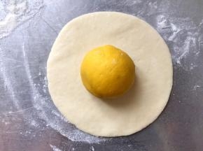取一个白色面团，擀成饼，放一个南瓜面团