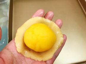取一份饼皮拍扁后包入一颗奶黄馅