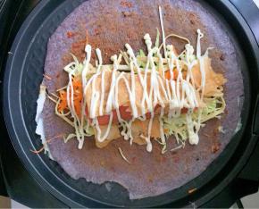 待鸡蛋液八九分熟了就把饼翻面，注意动作要轻，否则会破皮，在饼上刷上喜欢的辣酱或甜面酱，然后摆上蔬菜丝，再放上香肠，再放薄脆，最后挤上沙拉酱。从一侧包起，把蔬菜包在中心，出锅装盘