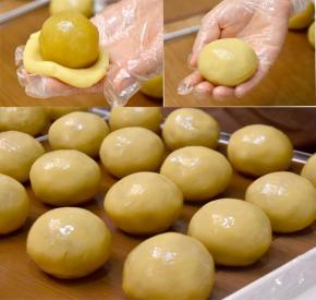 取一份饼皮压扁后包入莲蓉蛋黄馅料，用虎口把饼皮慢慢向上推，最后揉搓至饼皮完全包裹住馅料，收紧口，间隔开放在烤盘。