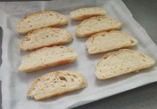 再把牛奶欧包切成1cm左右厚的片，放入垫有油纸的烤盘里