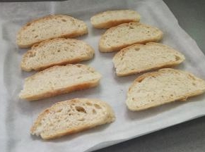 再把牛奶欧包切成1cm左右厚的片，放入垫有油纸的烤盘里