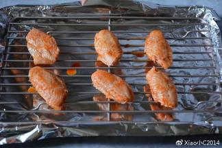 烤盘铺上锡纸，将鸡翅放在烤架上。刷上一层蜂蜜
